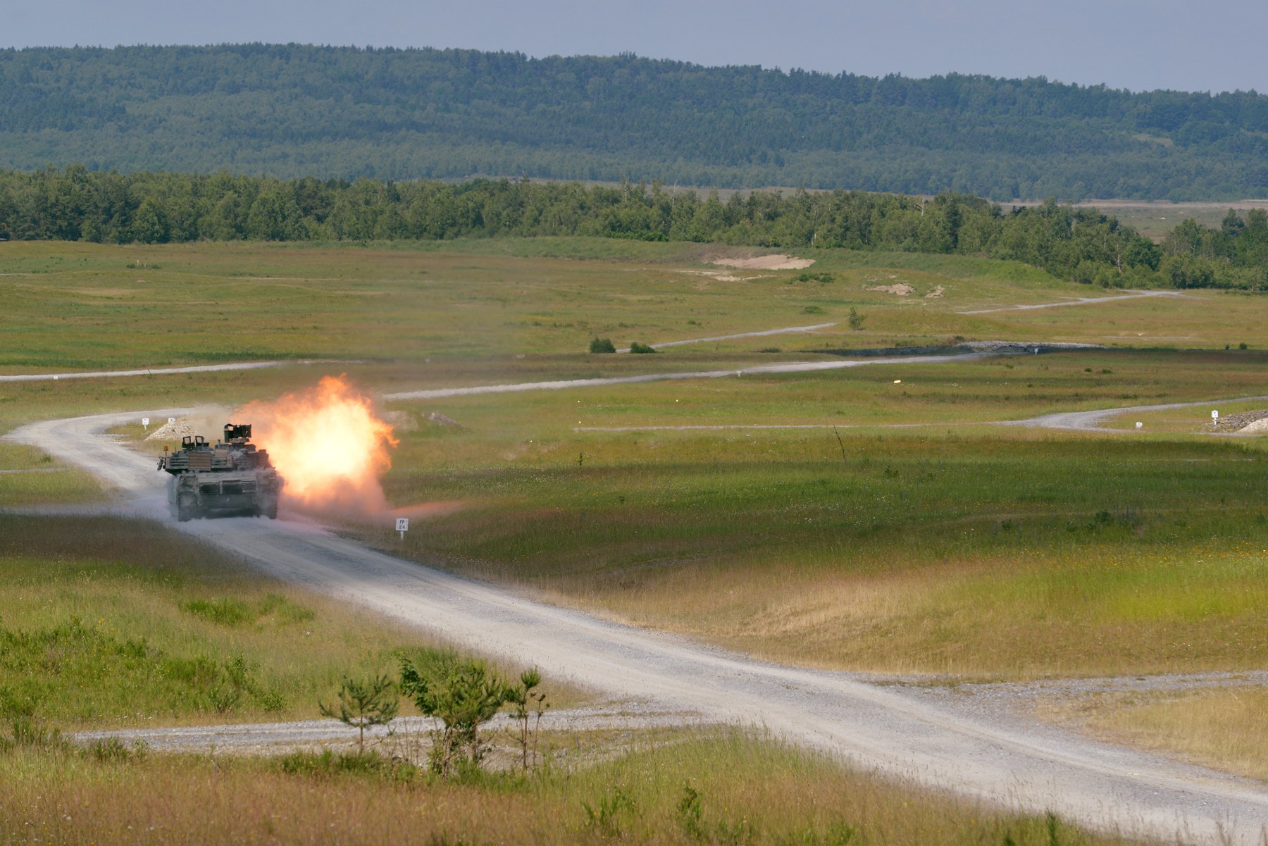 An M1A2 Abrams tank firing during training on a grassy range in Grafenwoehr, Germany.